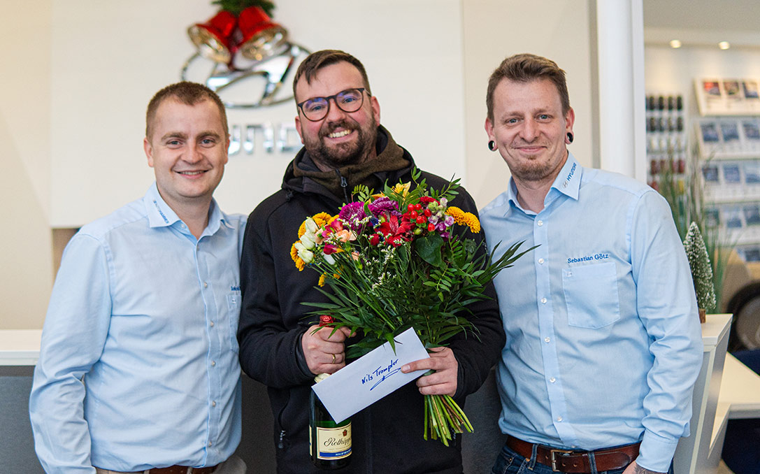 Drei Mitarbeiter bei der Verabschiedung eines Kollegen